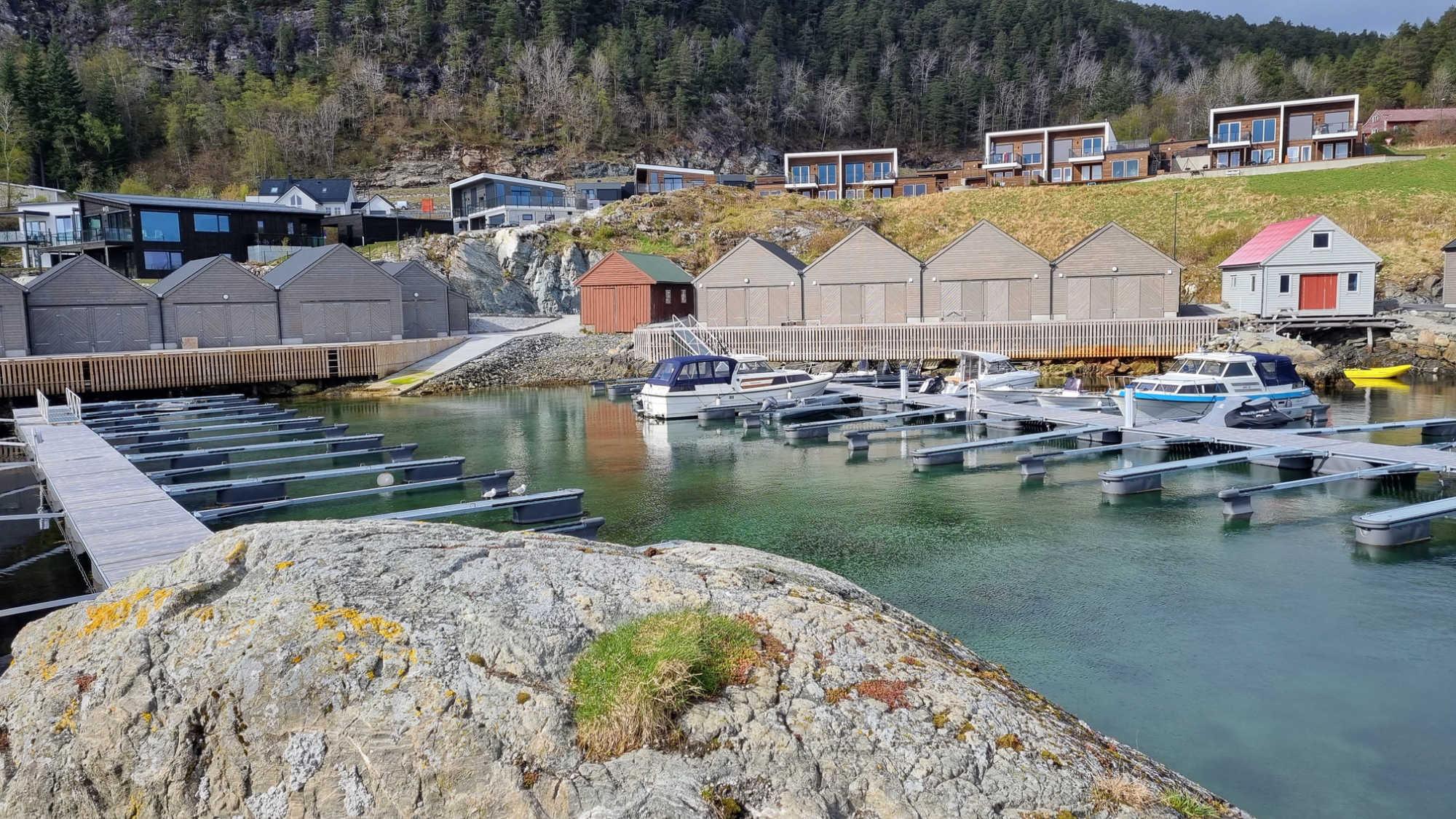 Småbåthamna på Instetunet med naust langs sjøen og nye hus i lia