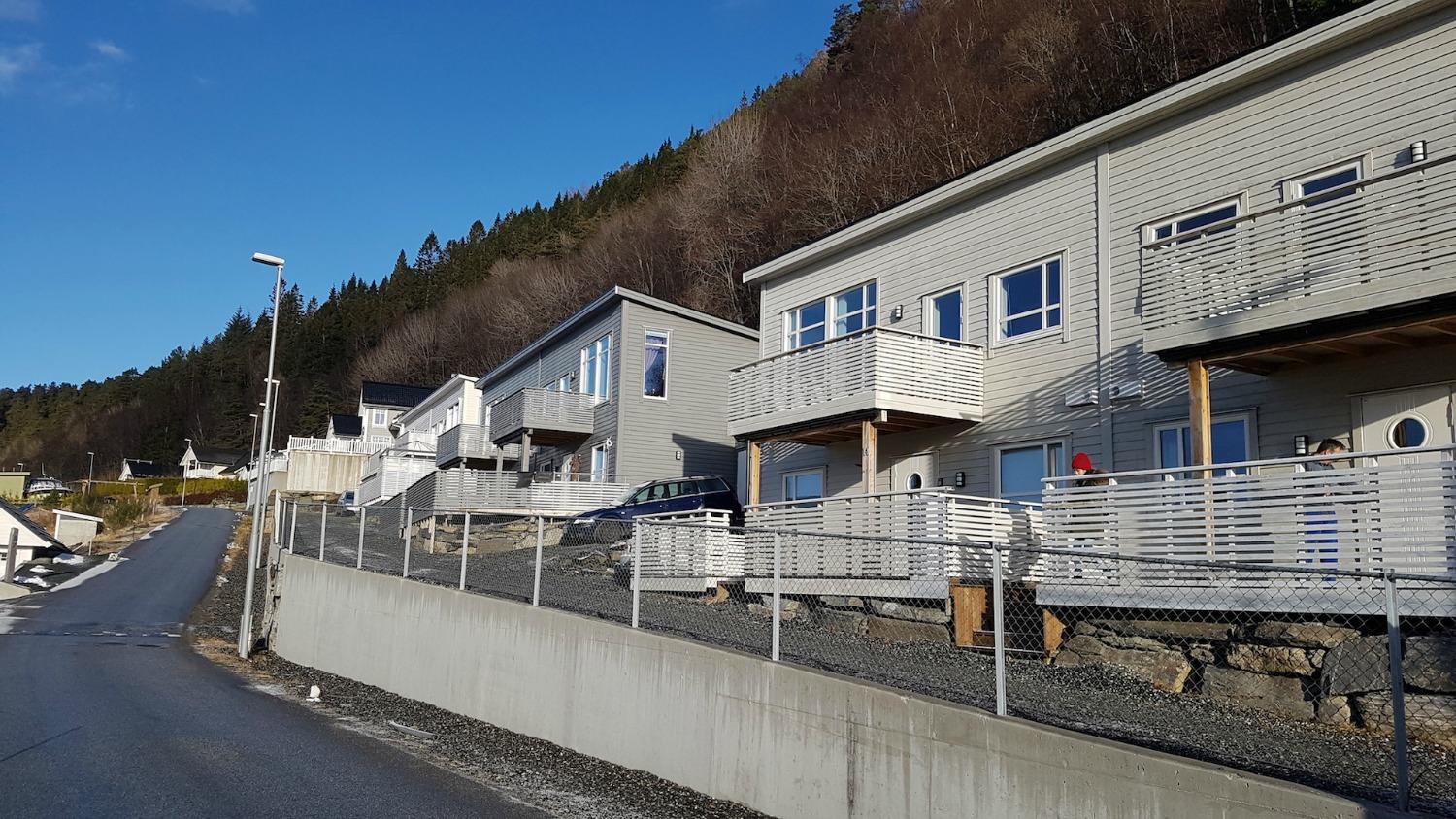 Rekke med tomannsbustader langs ein veg i lia