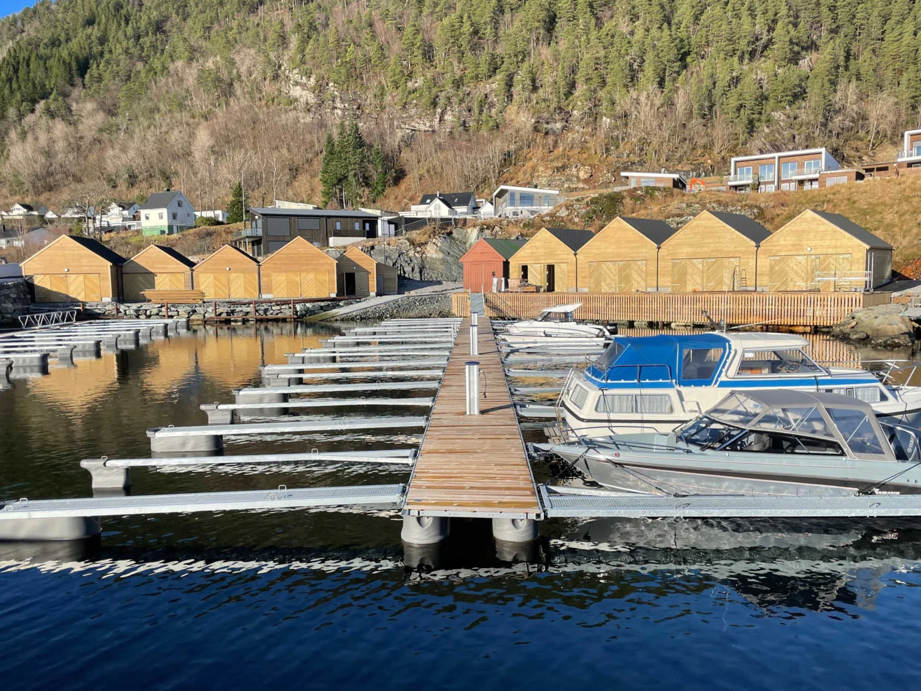 Naust og flytebryggjer ved sjøen på Instetunet, med bustader i lia bak